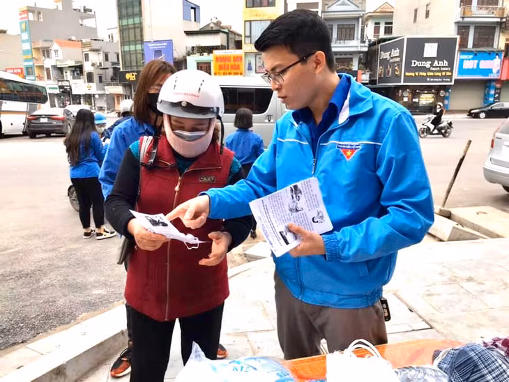 青年团员给居民发放防疫宣传单。