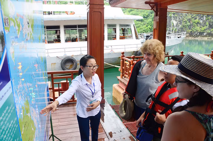 Du khách quốc tế nghe nhân viên Trung tâm giới thiệu về lịch sử hình thành làng chài Cửa Vạn trên Vịnh Hạ Long.