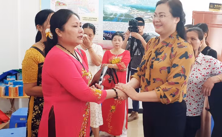 在东兴镇花溪社区的越南媳妇非常感动地握着我省妇女联合会代表的手。