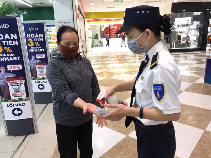 超市服务员给顾客喷上免洗手液。