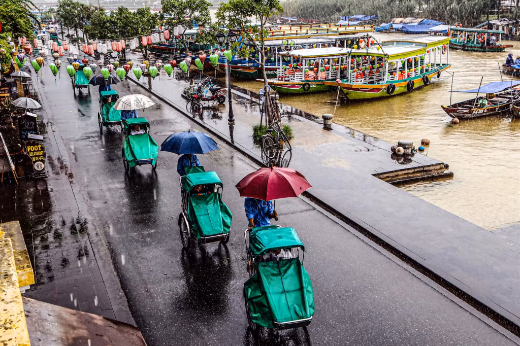 游客选择搭乘三轮车参观雨中的古城 Du khách chọn ngồi xe xích lô để dạo ngắm phố cổ trong mưa