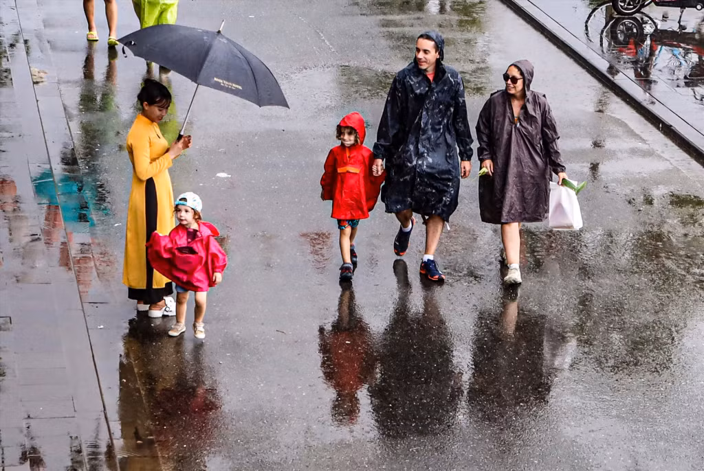 外国游客一家人选择披着雨衣参观雨中的古城，领略这一特殊时刻的美妙 Một gia đình du khách nước ngoài chọn cách mặc áo mưa đi ngắm phố cổ trong mưa để cảm nhận sự tuyệt vời của thời khắc đặc biệt này