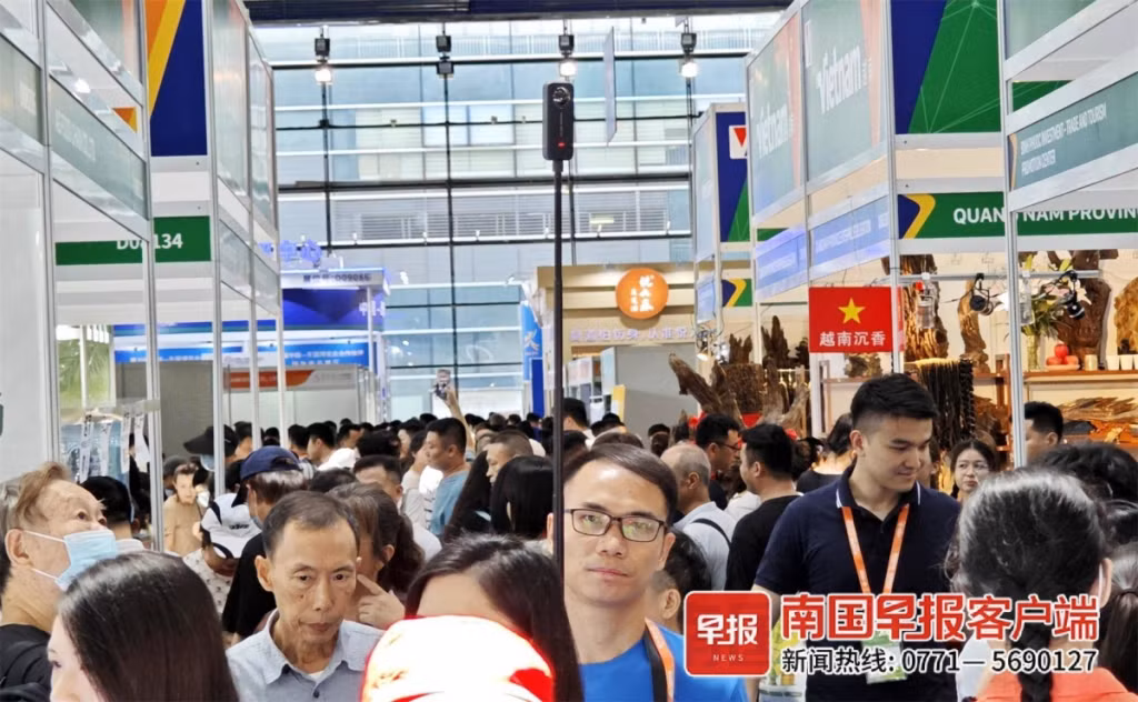 一名观众穿行于各展区，用高杆直播设备“流动式”直播。何定坚 摄 Một khán giả đi qua từng khu vực triển lãm, sử dụng gậy livestream theo phương thức "di động". Ảnh: Hà Định Kiên chụp