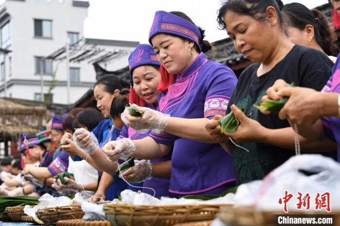 民众在参加包粽子比赛。 Người dân đang tham gia cuộc thi gói bánh chưng.
