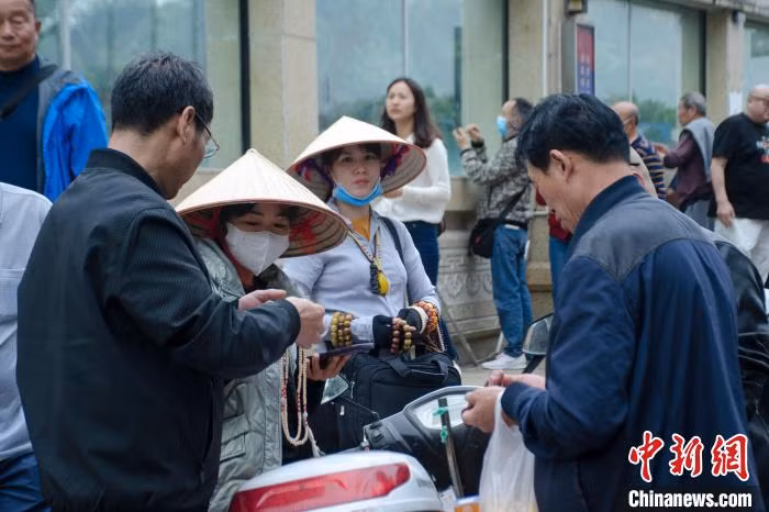 图为一名越南女子在东兴向中国游客推销她从越南带来的首饰。 Hình ảnh một phụ nữ Việt Nam đang chào bán sản phẩm đồ trang sức mang từ Việt Nam tới cho du khách Trung Quốc tại Đông Hưng.