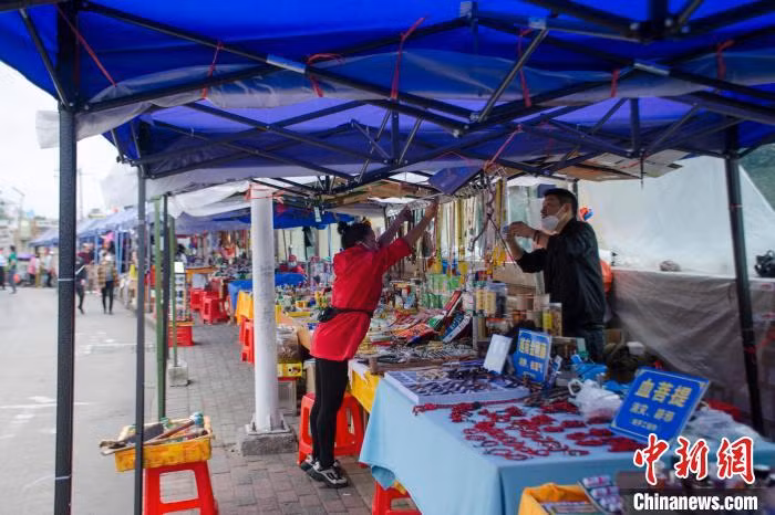 图为中越界河——北仑河边上的小商品街。 Hình ảnh du khách tại con phố nhỏ bán hàng hóa bên sông Bắc Luân – sông biên giới Trung – Việt.