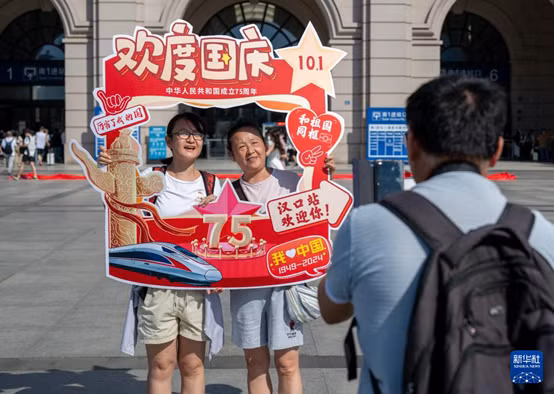 中国铁路武汉局集团有限公司在汉口火车站广场开展迎国庆快闪活动，旅客合影留念。 Công ty TNHH Cục Vũ Hán Tập đoàn Đường sắt Trung Quốc tổ chức hoạt động nhảy flash mob mừng đón Quốc Khánh tại Quảng trường nhà ga Hán Khẩu, hành khách dừng chân chụp hình lưu niệm.