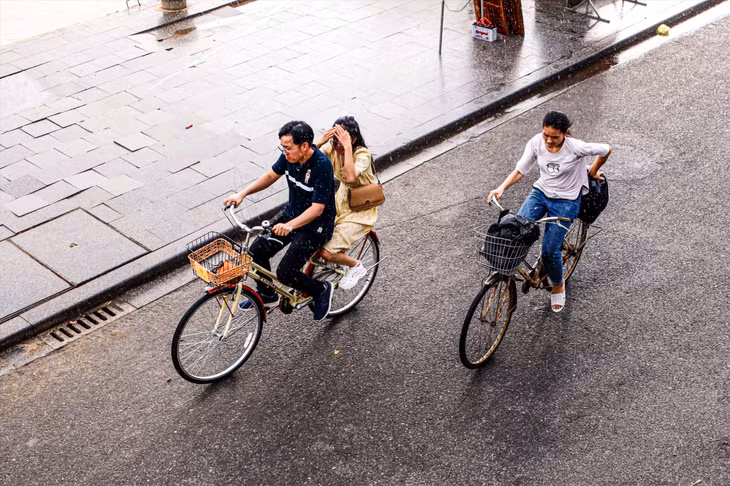 路上，骑自行车的人正匆忙“逃离”这突如其来的阵雨 Đạp xe “trốn” cơn mưa bất chợt