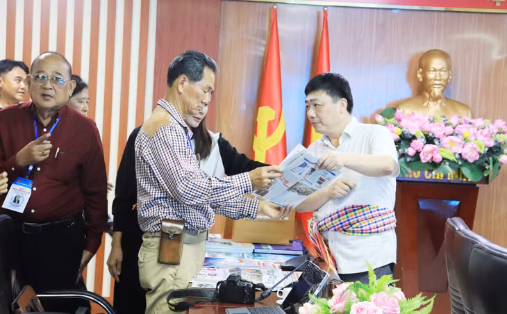 广宁省传媒中心代表向泰国工作代表团介绍本中心的纸质出版物。