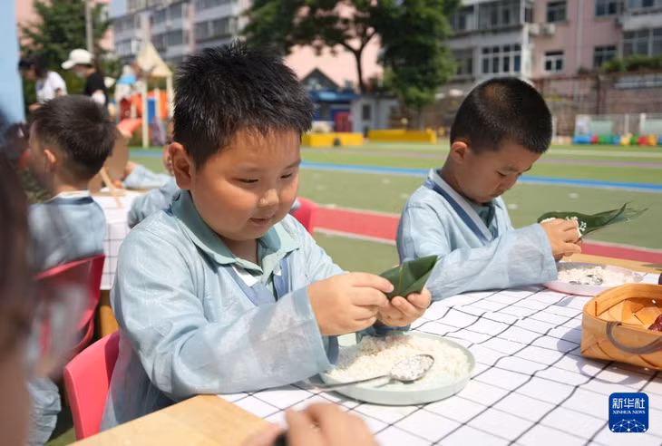 在山东省潍坊市潍城区实验小学幼儿园，孩子们在体验包粽子 Các em nhỏ tham gia trải nghiệm gói bánh chưng tại Trường Mầm non thuộc Trường tiểu học Thực nghiệm Duy Thành, Duy Phường, tỉnh Sơn Đông.