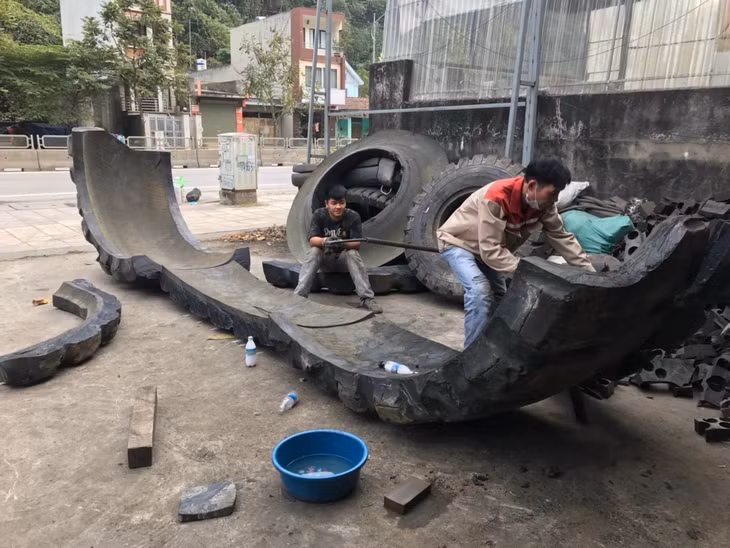轮胎回收厂的工人正在加工一条大轮胎。