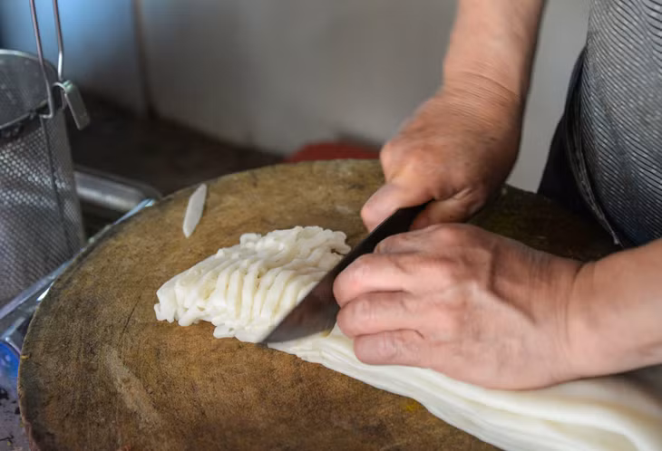 厨师将粉皮均匀切开摊放，新鲜度依旧，柔软耐嚼 Người chế biến thái bánh phở đều tăm tắp, còn nguyên độ tươi, vừa dai vừa mềm