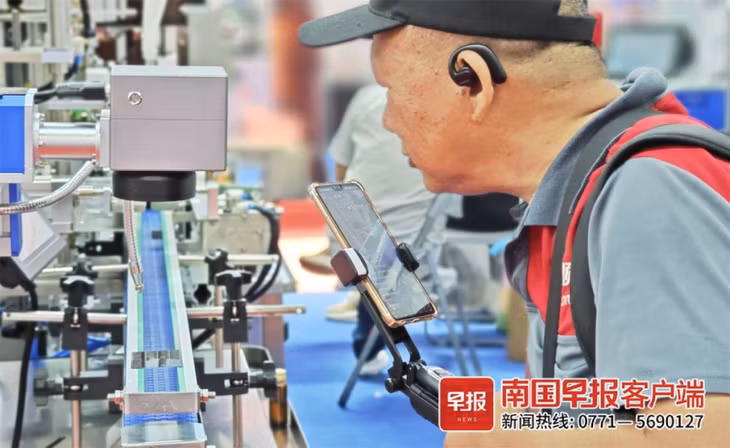 一名老年观众做直播，边走边解说。何定坚 摄 Một khán giả cao tuổi livestream, vừa đi vừa giải thích. Ảnh: Hà Định Kiên chụp