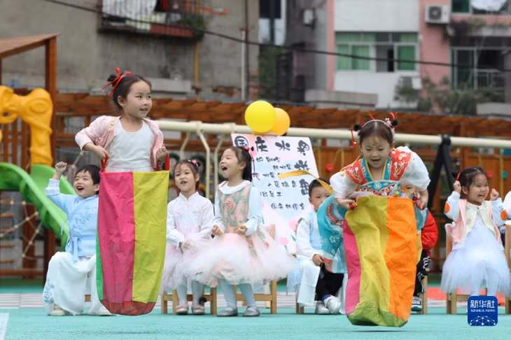 四川省广安市武胜县迎宾幼儿园的小朋友穿上跳袋玩“嫦娥奔月”的游戏。夏俊林 摄 Trẻ em Trường mẫu giáo Nghênh Tân, huyện Vũ Thắng, thành phố Quảng An, tỉnh Tứ Xuyên đeo túi nhảy chơi trò chơi “Hằng Nga bôn nguyệt (Chị Hằng lên Cung trăng)”. Hạ Tuấn Lâm chụp